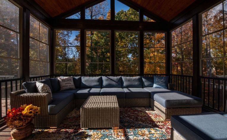 A sunroom with patio sofa set in grey with blue cushions
